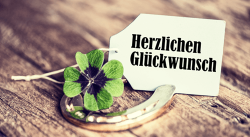 Ein Kleeblatt das auf einem goldenen Hufeisen liegt, dahinter ein Etikett auf dem steht