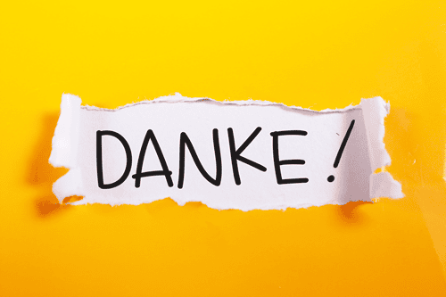 Der Schriftzug "DANKE!" auf einem weißen Stück Papier vor einem gelben Hintergrund