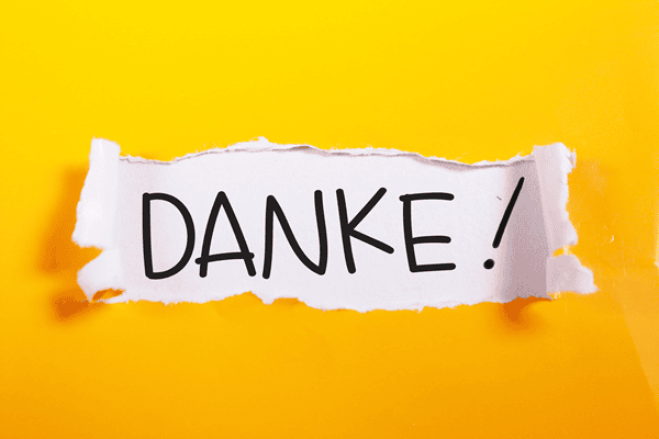 Der Schriftzug "DANKE!" auf einem weißen Stück Papier vor einem gelben Hintergrund