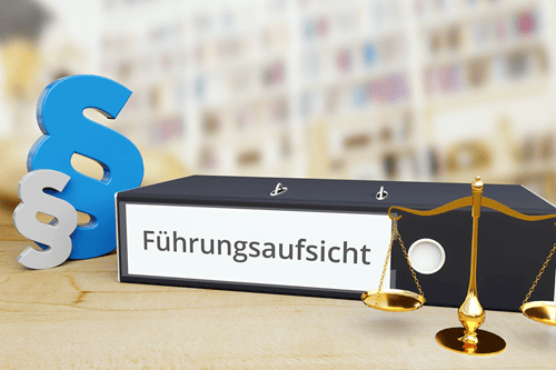 Ein Aktenordner mit der Aufschrift "Führungsaufsicht", davor eine Balkenwage, dahinter zwei Paragraphenzeichen