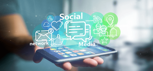 Ein Smartphone das mit dem Display nach oben auf einer Handfläche liegt, darüber Grafiken und die Schriftzüge "Social", "network" und "Media"