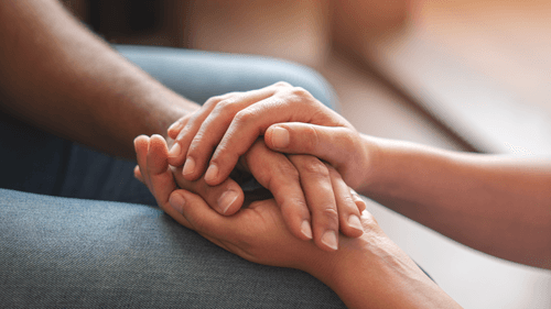 Eine Hand die von zwei anderen Händen umschlossen wird